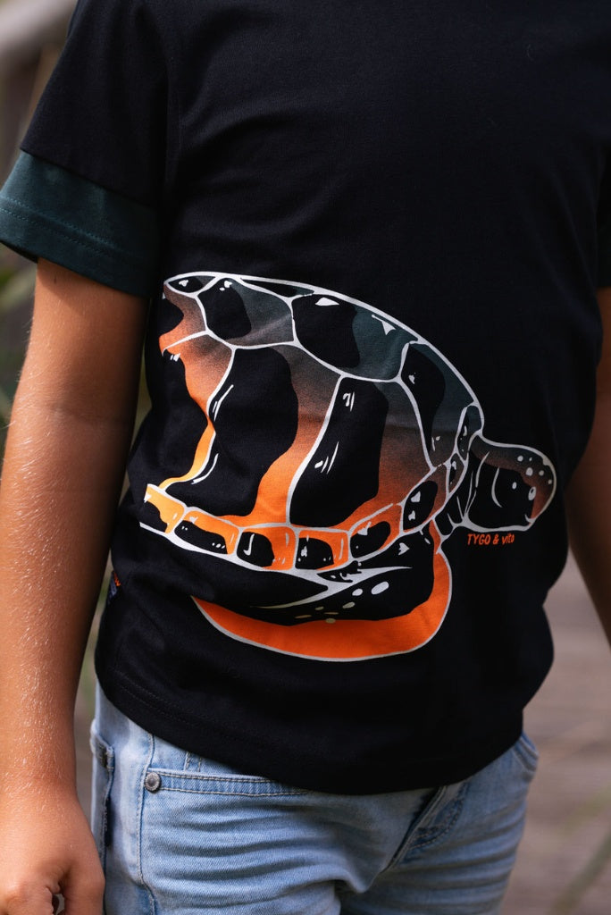 Boy wearing a black t-shirt Toby with a turtle graphic design.