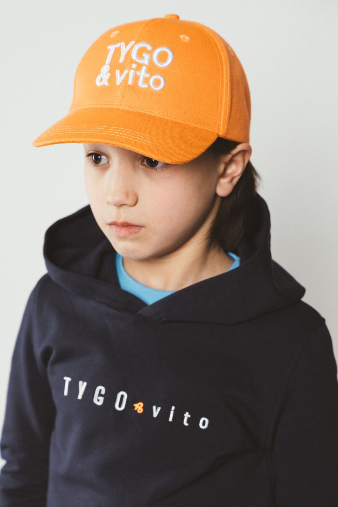 Boy wearing an orange cap and black hoodie with &