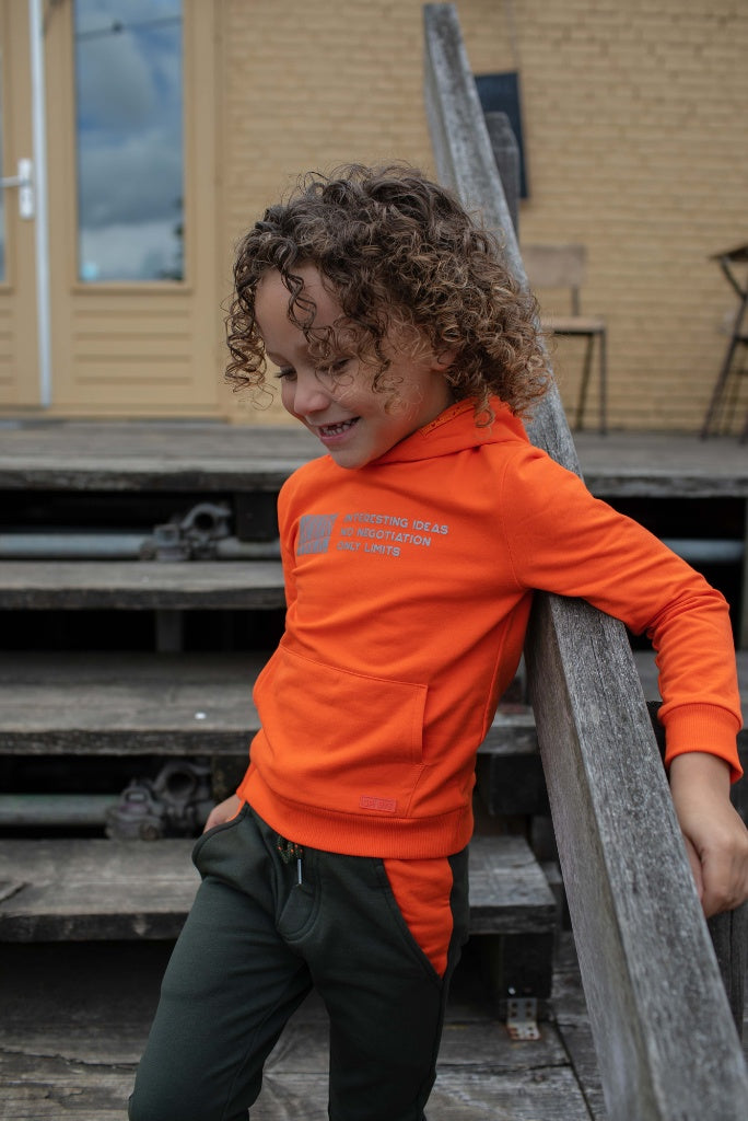 Boy standing and wearing the orange hoodie Knox by Quapi