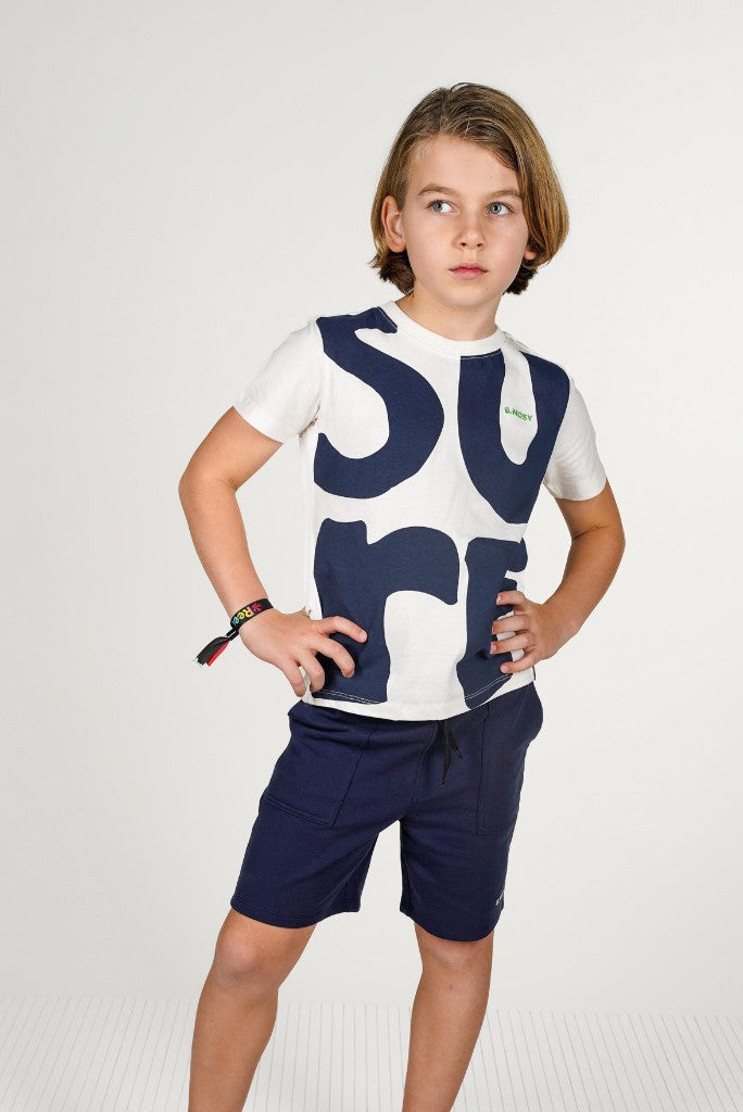 Boy wearing a white t-shirt with blue text and navy shorts Pax by B.Nosy on a white background