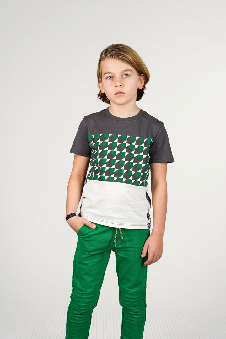 Boy wearing a gray t-shirt with a green and white pattern and green pants on a white background