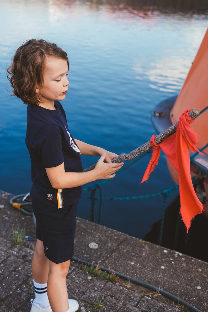 Child holding a rope attached to a boat near a body of water