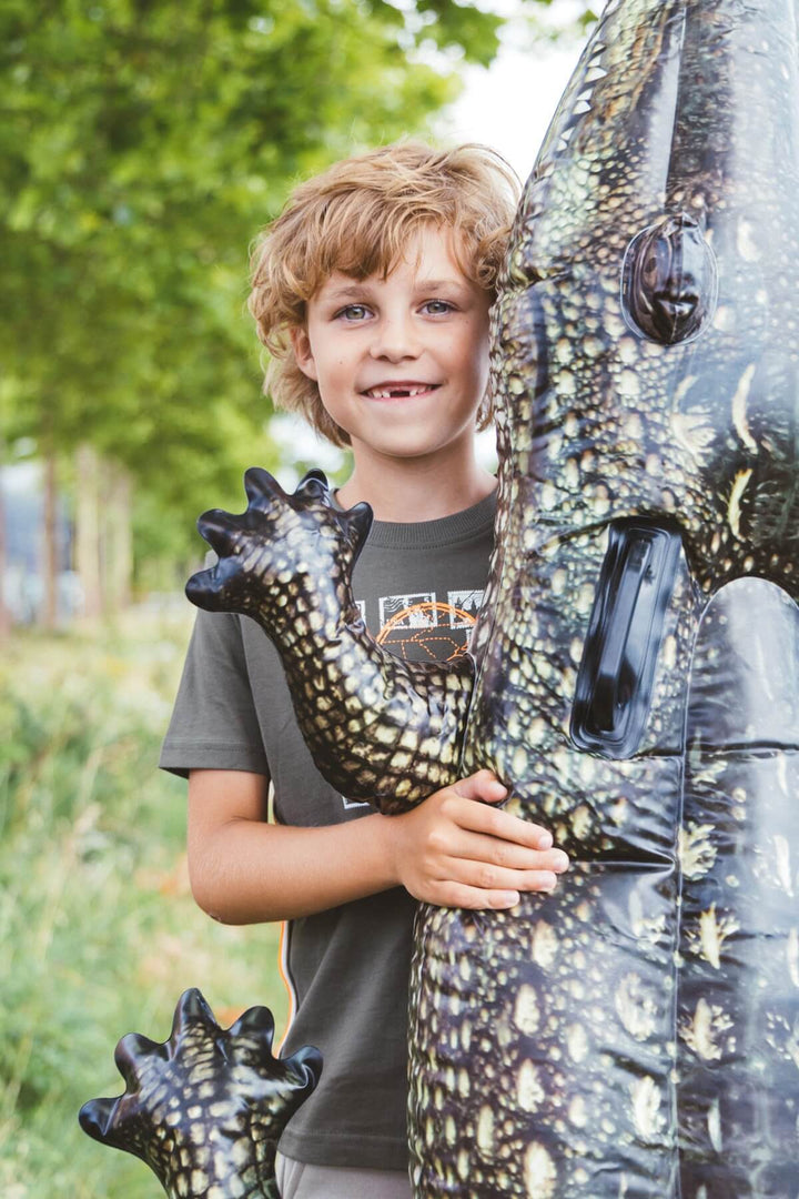 Child holding a dinosaur-shaped inflatable toy outdoors