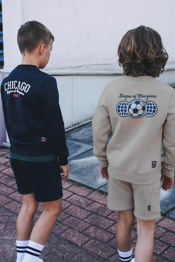Two children wearing sweatshirts with visible branding on a sidewalk.