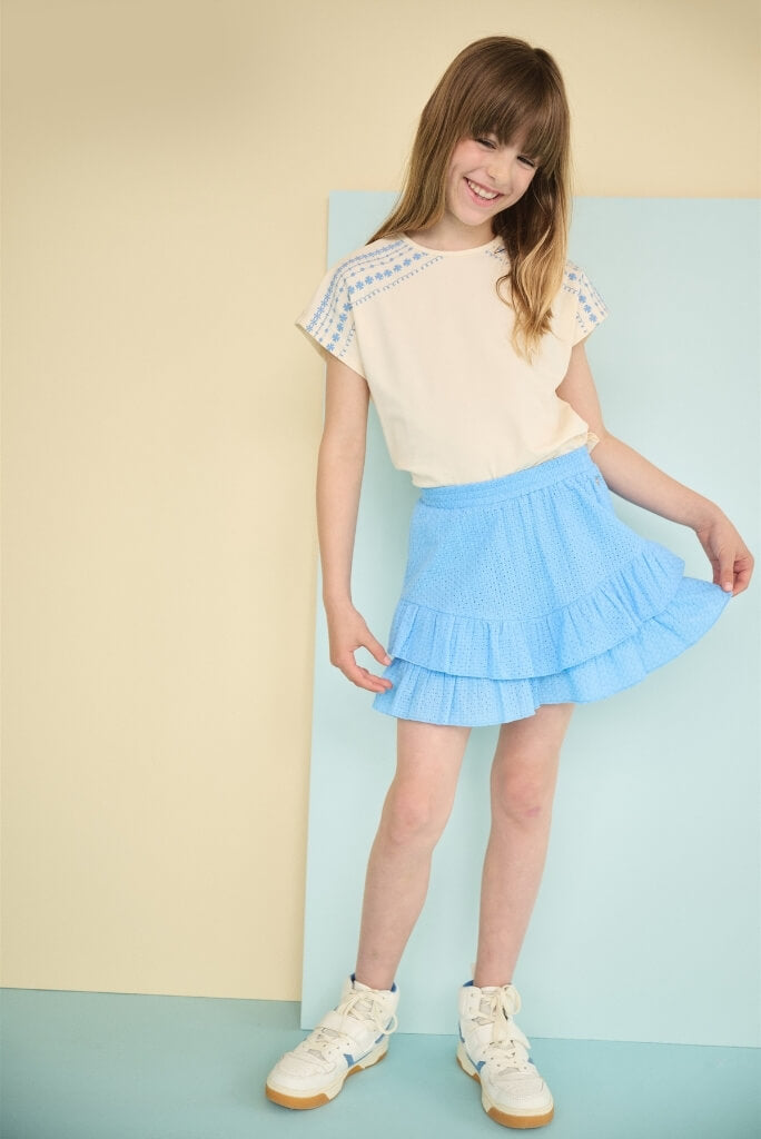Smiling girl looking to the side and wearing the blue skirt Naia by NONO