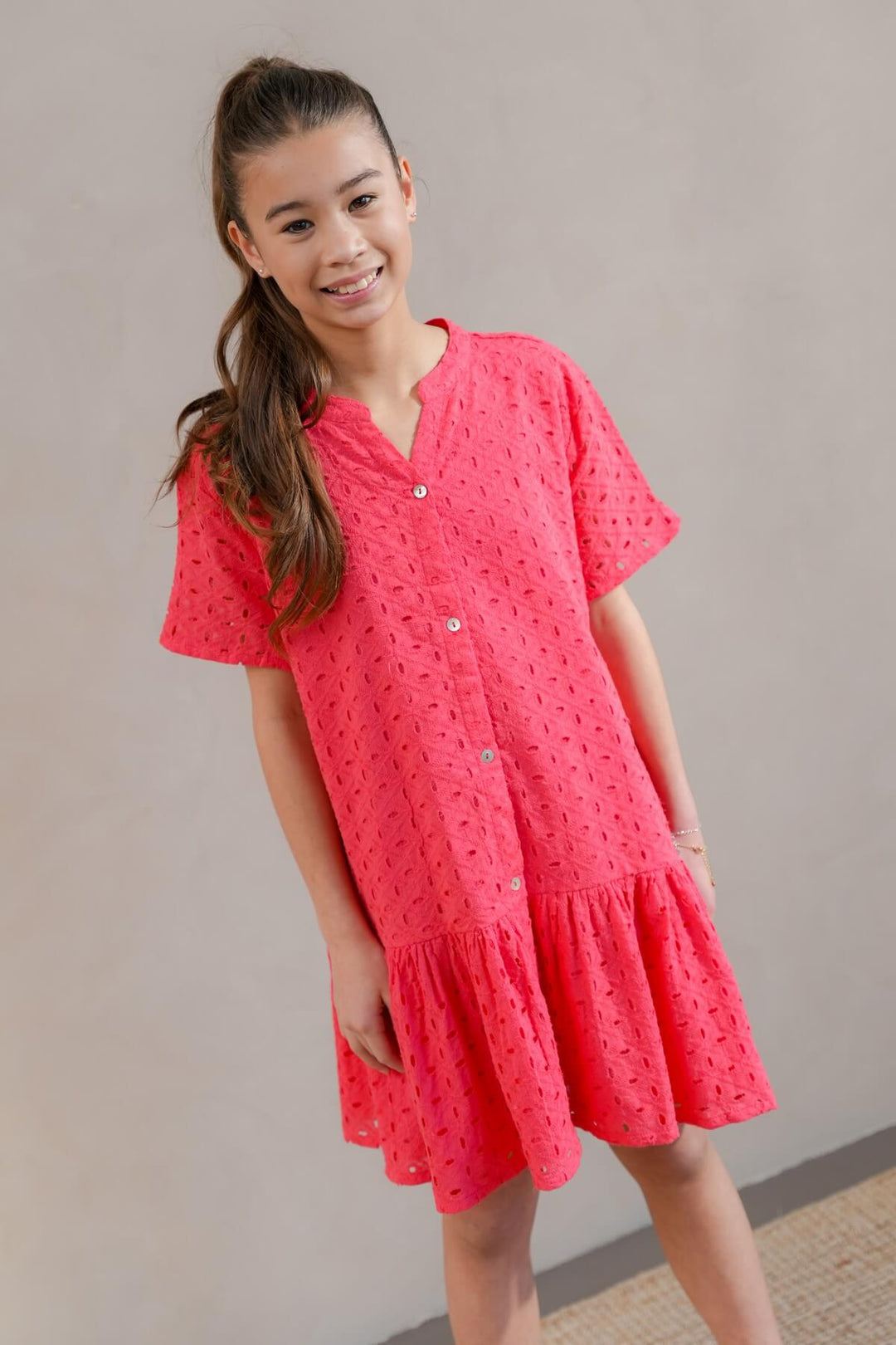 Young girl wearing a pink dress against a plain background