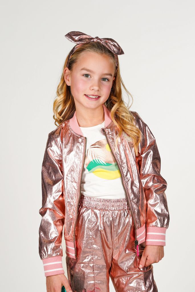 Young girl wearing a rose gold jacket and colorful outfit on a white background