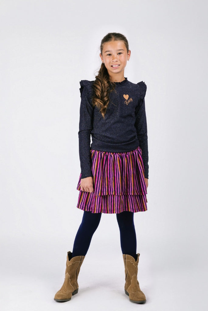 Young girl wearing a dark sweater with ruffled shoulders, a striped skirt, and brown boots on a white background