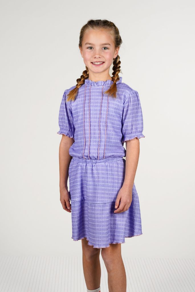 Young girl wearing a purple checkered dress Dotty on a white background