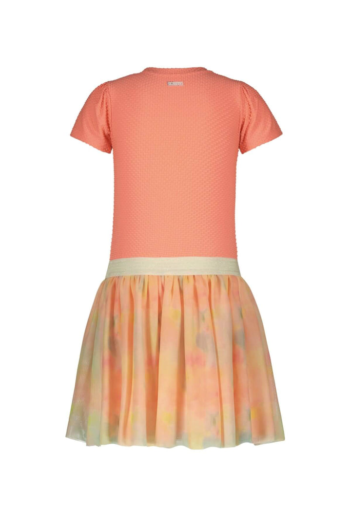 Back view of a short-sleeve dress with a textured coral-orange top and a pleated tulle skirt in a soft pastel tie-dye pattern of orange, yellow, and green, featuring a cream waistband.