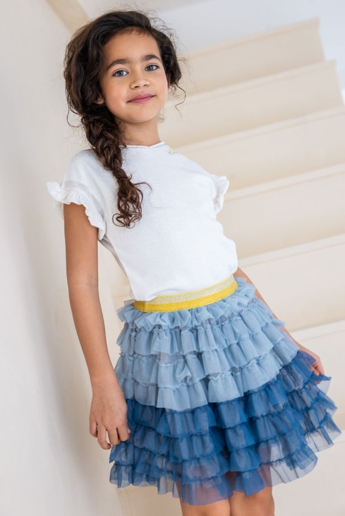 Girl wearing the metallic ruffle sleeve tee with a blue skirt