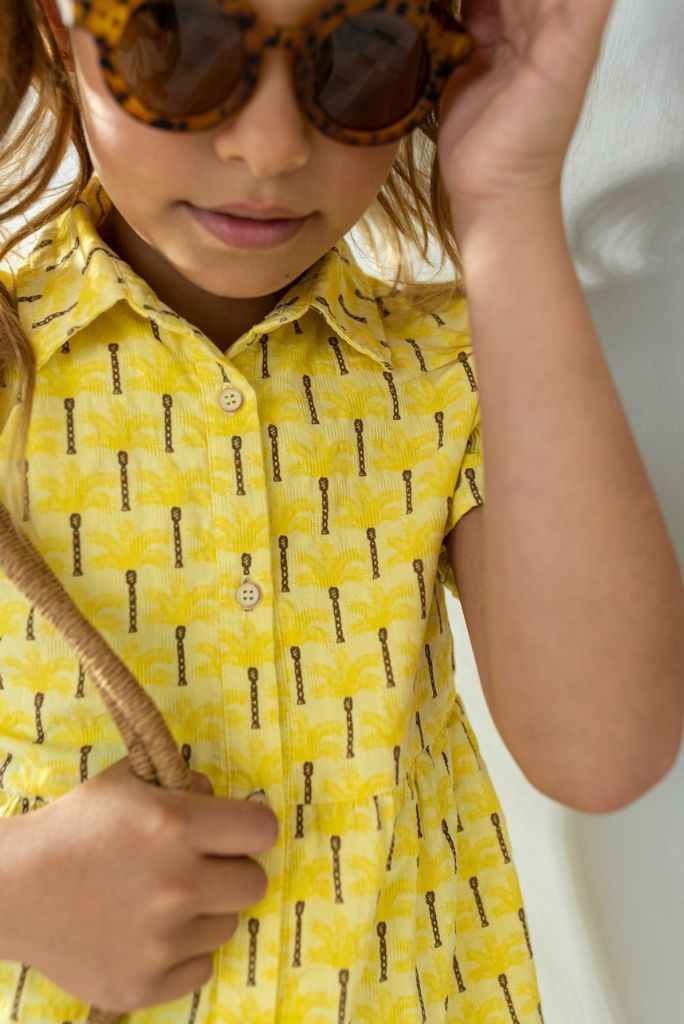 Close view of the girl wearing the yellow palm print dress by Like FLO