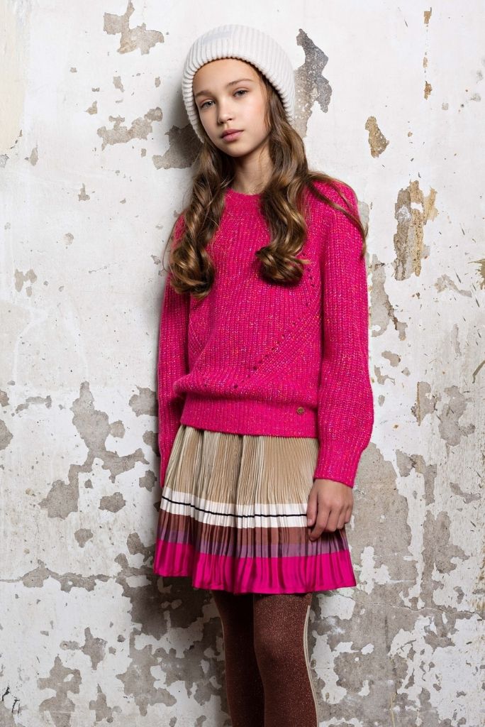 Girl wearing the Nulan pleated satin skirt with a pink jumper