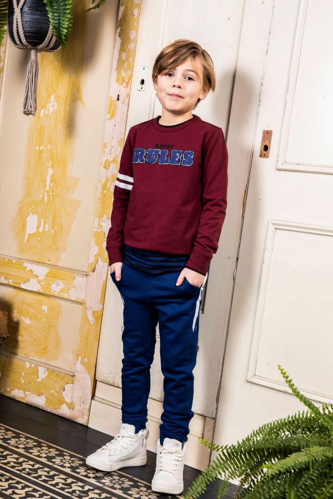 Boy wearing the winter red jumper with navy trackpants