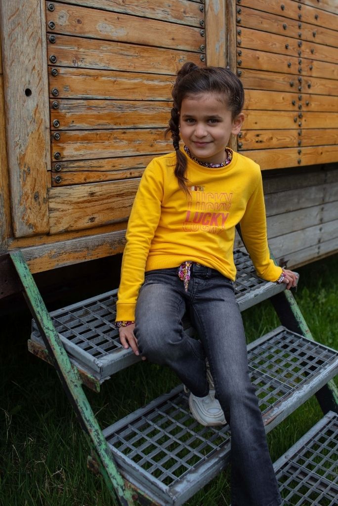 Another view of the girl wearing the yellow jumper Kato and sitting down